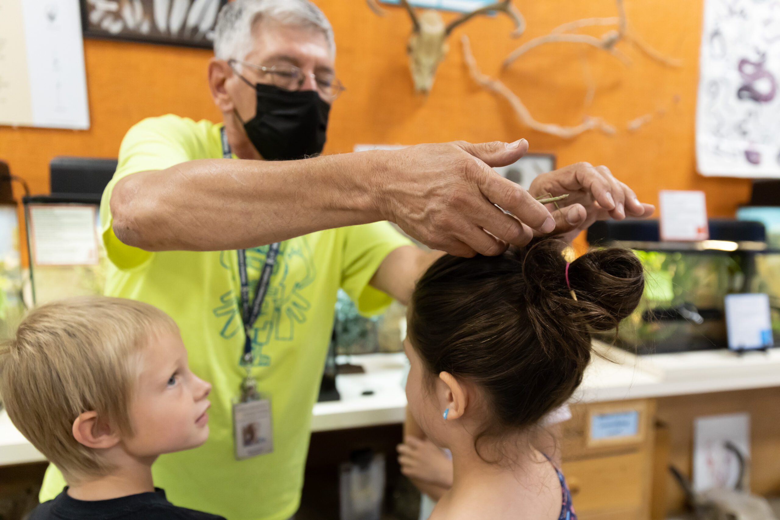 Museum employee placing a bug on a small visitors head