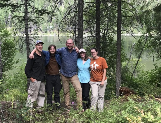 Group of five scientists in the forest in front of a river